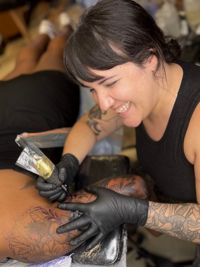 villustrated valentina cekovski tattooing woman smiling with gloves on hands and rotary tattoo machine